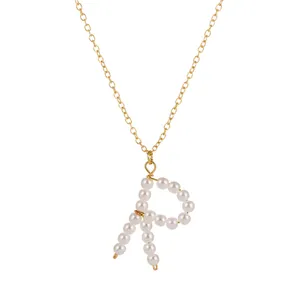 Collana con catena dorata e pendente delicato di perle lettera R in primo piano.