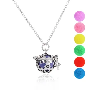 Silver hollow aroma diffuser pendant necklace detail view with colorful pom pom balls.