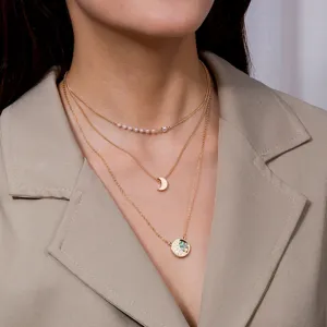 Vue détaillée d'un collier doré élégant à trois rangs avec perles et pendentif lune.