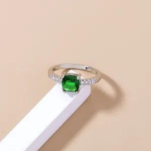 Primo piano dell'elegante anello argentato con pietra centrale verde e zirconi brillanti.