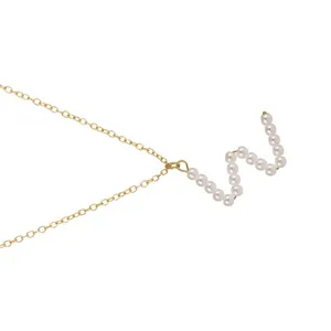 Elegante collana con catenina dorata e lettera iniziale in perla vista di dettaglio.