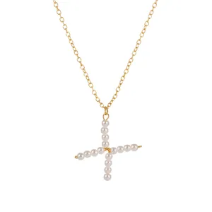 Vista dettagliata di una collana a catena dorata con elegante ciondolo a croce di perle.
