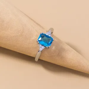 Primo piano dettagliato di un anello scintillante con pietra preziosa blu e zirconi.