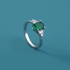 Primo piano dettaglio di anello in rame argentato con zircone verde ovale e piccole pietre.