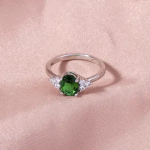 Dettaglio in primo piano di anello donna argento con gemma verde ovale e zirconi brillanti.