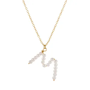 Primo piano dettaglio della collana con catena in oro elegante e pendente lettera perla.