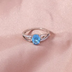 Elegante anello in rame argentato con zircone blu ovale e pietre micro-incastonate.