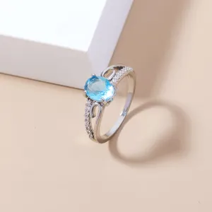 Anello di colore argento con pietra zircone azzurro ovale e delicati cristalli pavé laterali.