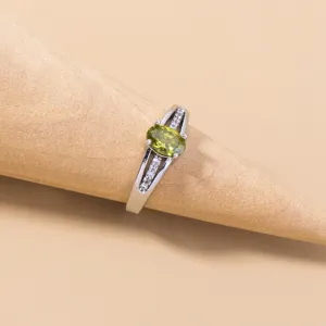 Vista dettagliata di un anello da donna argentato con zircone verde ovale e piccoli pavè.