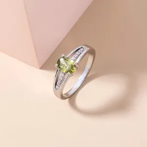 Ravvicinato dettaglio di un anello argentato da donna con gemma di zircone verde ovale.