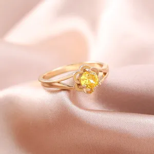 Primo piano di anello placcato oro con zircone giallo scintillante dal design floreale elegante.