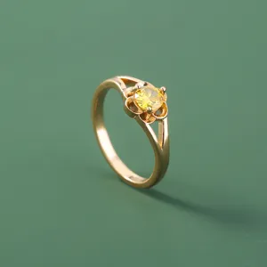 Primo piano anello minimale in rame dorato con zircone giallo brillante in montatura.