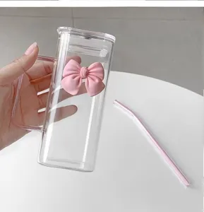 Clear minimalist square glass cup with pink bow handle and straw for coffee milk.