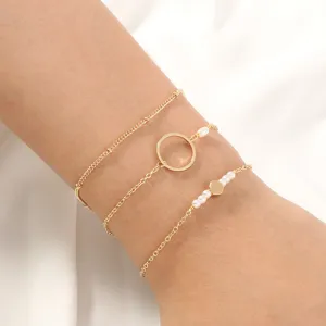 Conjunto de pulseras de cadena dorada multicapa con perlas delicadas y anillos geométricos.