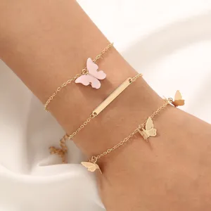 Juego de pulseras multicapa doradas con delicados dijes de mariposa rosas y metálicos.