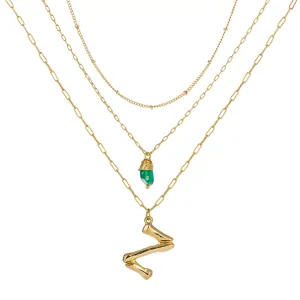 Vue détaillée du collier doré à trois couches avec son pendentif abstrait et unique.