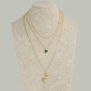 Ensemble de colliers en chaîne dorée superposée avec pierre verte et pendentif en métal.