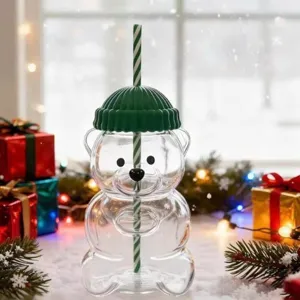 Cute bear shaped glass cup detail with green hat lid and straw in festive Christmas setting