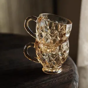 Detalle de taza de cafe de vidrio ambar con patron en relieve y asa practica para el hogar.