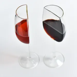 Closeup detail of creative half wine glass set, transparent glass goblet with unique sliced design.