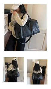 Detail view of large capacity black soft leather travel duffel bag with shoulder strap.