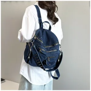 Denim backpack back view detail, vintage dark blue wash, multi zipper pockets and metal studs.