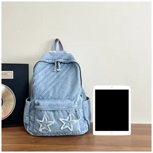 Denim canvas backpack detailed view showing washed blue texture, star patches and pocket design.