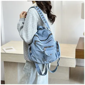 Casual multi-pocket denim backpack detail view, featuring metallic studs and sturdy zippers.