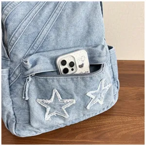 Denim backpack front pocket detail showing washed fabric texture and frayed star patch design.