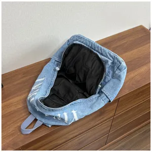 Washed denim backpack detail showing spacious interior compartments and black lining design.