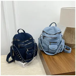 Detail view of casual denim backpacks featuring multi-zipper pockets and rivet shoulder straps.