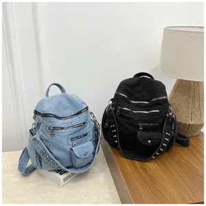 Detailed view of the vintage denim backpack featuring multiple zippers and metal rivets.