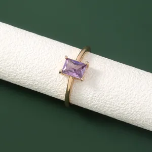 Detailopname van een delicate paarse zirkonia ring op een witte cilinderstandaard.
