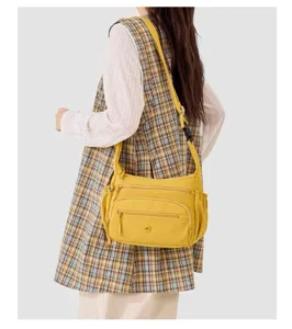 Detailed view of the yellow nylon shoulder bag showing multiple zipper pockets and strap.