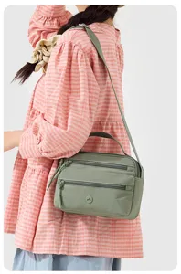 Sage green nylon crossbody bag with multi-zip compartments and top handle for women.