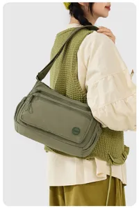 Detailed shot of women green nylon crossbody bag, multi-pocket design, stylish shoulder strap.