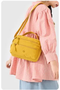 Yellow nylon crossbody bag detail, multi-pocket design with zipper and shoulder strap.