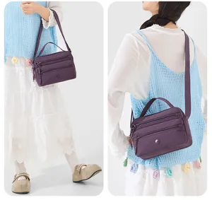 Detailed view of the casual purple nylon crossbody bag showing multiple zipper compartments and handle.