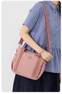 Detail view of the pink nylon shoulder bag featuring side pleats and adjustable strap.