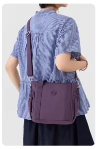 Detail view of the casual purple nylon crossbody bag showing shoulder strap and side pleats.
