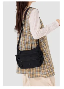 Detail view of the black nylon crossbody bag featuring multi-pocket design and adjustable strap.