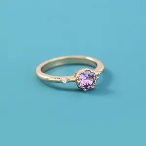 Close-up van vergulde paarse zirkoon ring, elegant vrouwen vinger sieraden accessoire.