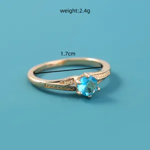 Vergulde ring met levendige blauwe zirkonia steen en delicate stenen aan de zijkanten.