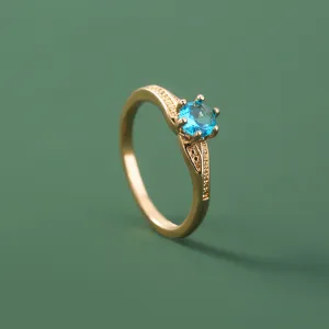 Close-up detail van de elegante vergulde ring met een sprankelende blauwe zirkoon.