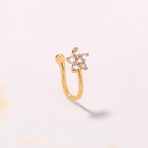 Dettaglio in primo piano di un anello da naso dorato a fiore con zirconi scintillanti.