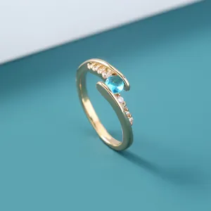 Gedetailleerde close-up van de goudkleurige verstelbare ring met helderblauwe zirkoon.