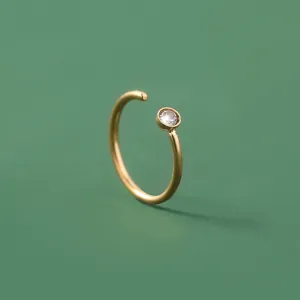 Nahaufnahme Detail des minimalistischen goldenen offenen Nasenrings mit einem klaren Zirkoniastein.