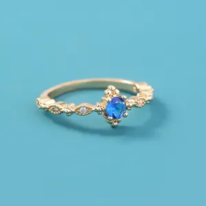 Close-up van de elegante vergulde ring met een stralende blauwe zirkoon in het midden.