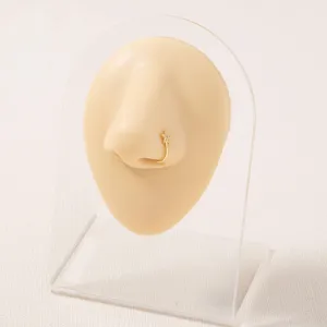 Vista dettagliata di un delicato anello da naso dorato con charm a stella su supporto.