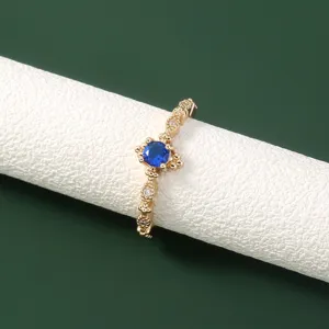 Gedetailleerde close-up van een gouden ring met een blauwe steen en sprankelende kristaldetails.